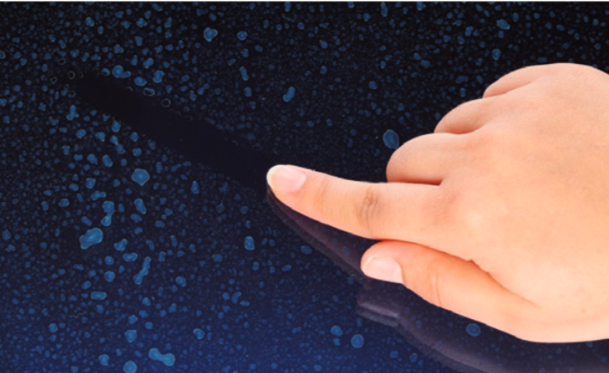 Finger zieht eine Linie auf einer verkalkten Glasoberfläche